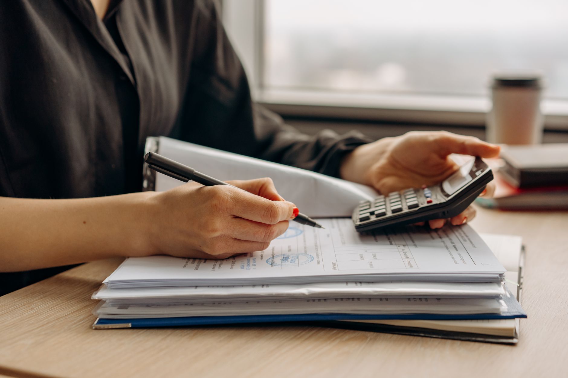 Homeowner planning a mold removal budget with a calculator and paperwork