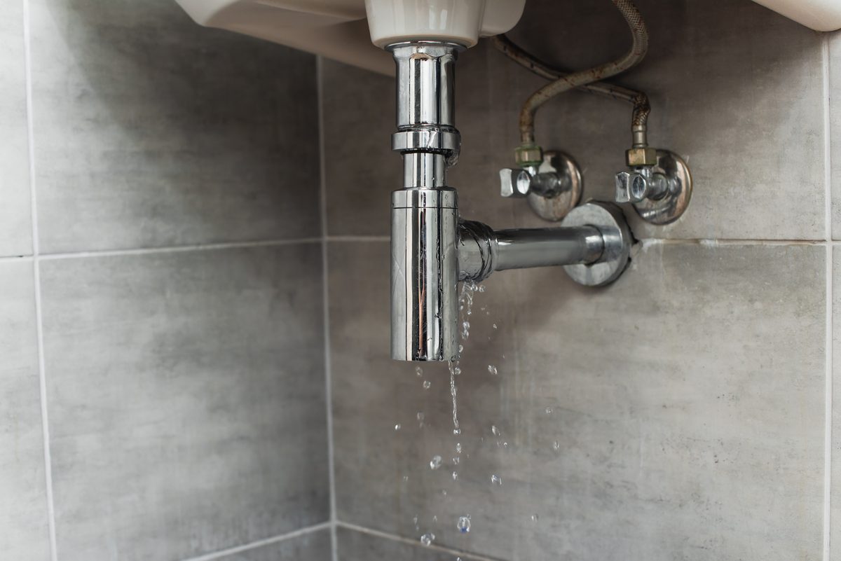 Water dripping from chrome plumbing under a sink