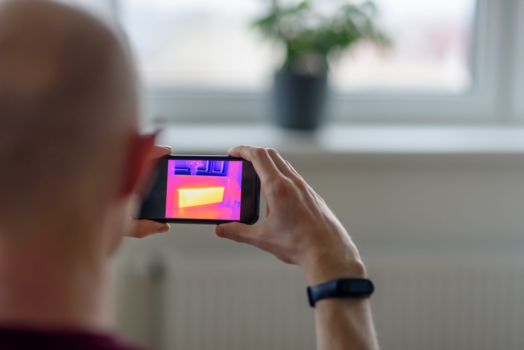 Person scanning a wall with a thermal imaging camera on a smartphone